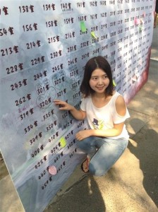 一位女生指著自己的宿舍門牌號碼留影