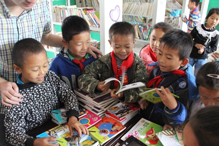 雲南省寧洱縣溫泉小學的同學們在圖書室翻閱新到的圖書